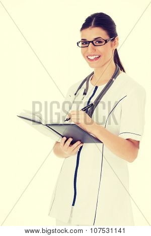 Young female doctor wirting in a book