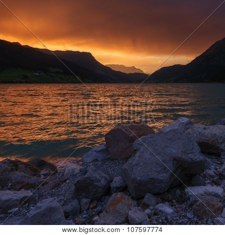Beautiful view of the lake Resia. Dramatic sky and colorful sunset. Alps, Italy, Europe.