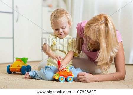Child boy and his mother repair toy car at home