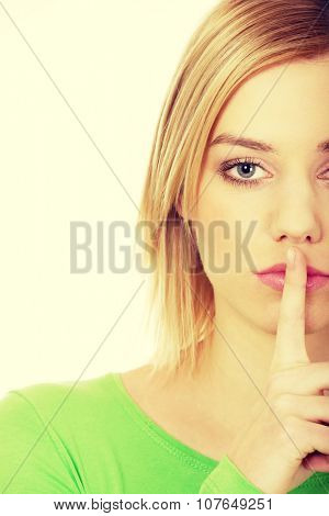 Caucasian woman making hush gesture.