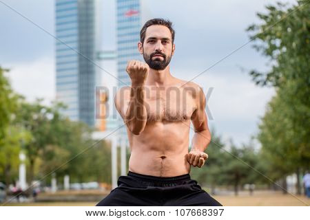 Mann practicing qigong outdoors, office building in background