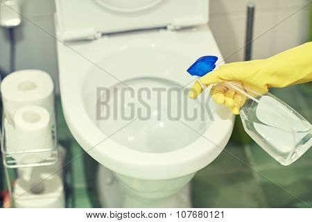 people, housework and housekeeping concept - close up of hand in rubber glove with detergent cleaning toilet pan