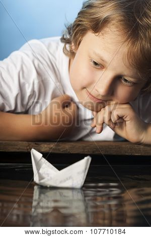 boy play in paper ship in water puddel