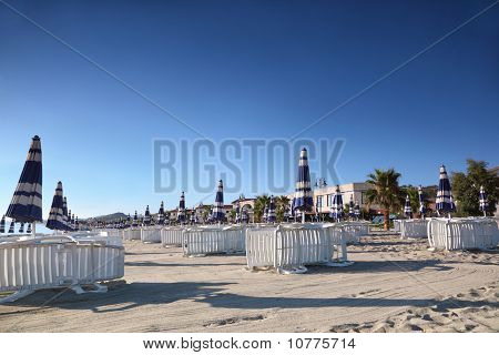 Sonnenliege mit Sonnenschirmen sind ordentlich erbaute Zeilen Morgen am Strand