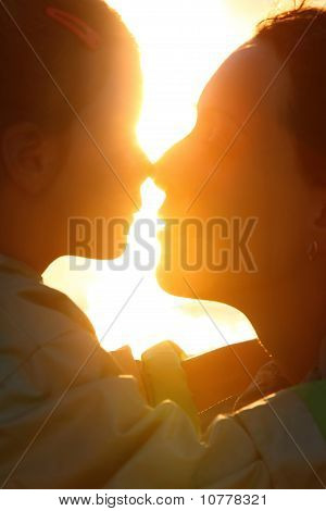 Мать с дочерью профиль на моря напротив солнца и трогательно носы