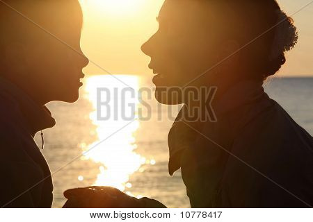 Женщина с мальчика сидят на берегу напротив солнца