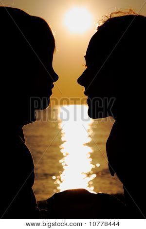 Силуэты матери и сына в вечер на берегу моря