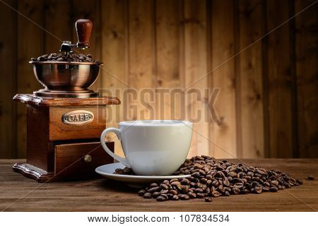 still life with coffee beans and old coffee mill on the wooden background  