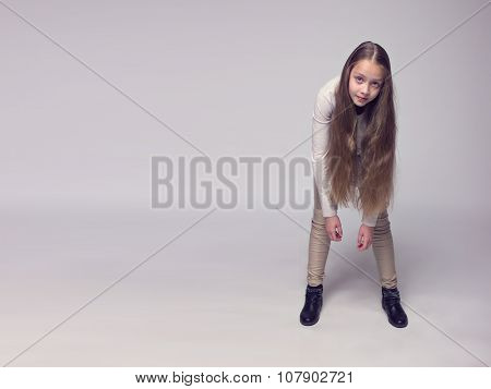 funny teenage girl fashionably dressed standing on a gray background
