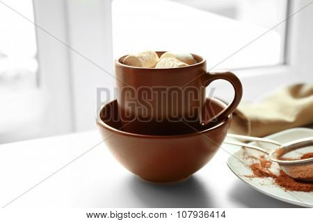 Cup of coffee with marsh mellow on a table in kitchen