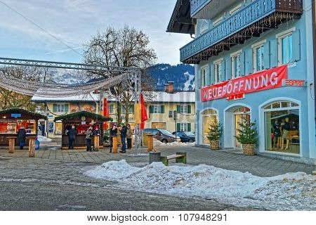 GARMISCH-PARTENKIRCHEN GERMANY - JANUARY 06 2015: Square in Garmisch-Partenkirchen with houses decorated for the winter holidays and unidentified people eating traditional Christmas food