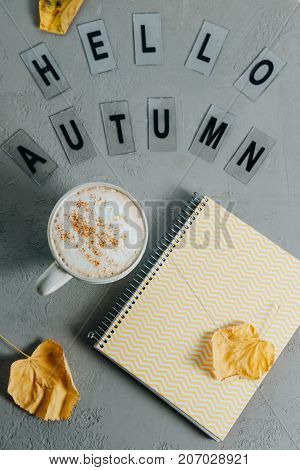 Flat Lay Comosition: Letters With The Text Hello Autumn, Notebook And Coffee On A Gray Background