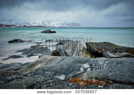 Waves of Norwegian sea on rocky beach of fjord. Ramberg beach, Lofoten islands, Norway