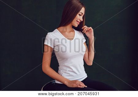 Woman with a big breast in a white T-shirt on dark background. Mock-up.