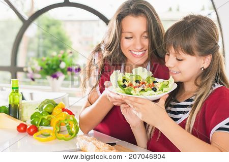 Happy family cooking salad. Children. Kid. Vegetarian meal at kitchen. Funny sisters making salad. Healthy lifestyle. Recipe of vitamins nutrition