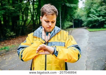 man measuring his pulse while running in autumn park