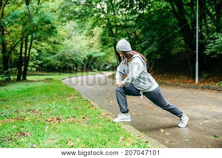 woman stretching in city park in autumn day