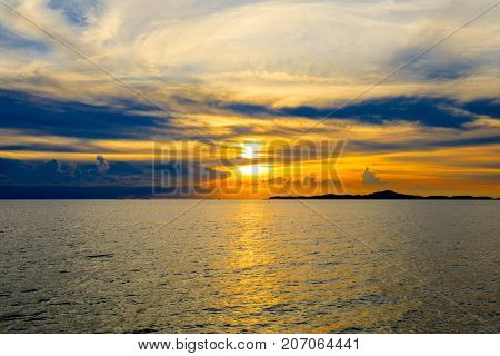 Dramatic sky at sunset or evening time over sea or ocean with golden or orange light tone.