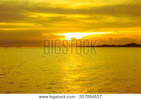 Dramatic sky at sunset or evening time over sea or ocean with golden or orange light tone.