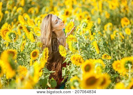 Happy woman on a flower field enjoys herself.