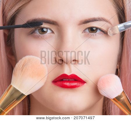 Beautiful young woman with makeup brushes around face