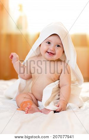 Adorable baby girl sitting in hooded towel after bathing
