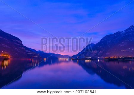 Night landscape. Royal blue. The mountain range the light of lanterns and lamps are reflected in the lake long exposure