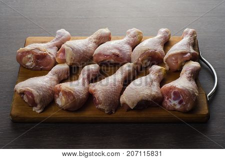 Fresh raw chicken legs arrangement on a kitchen cutting board
