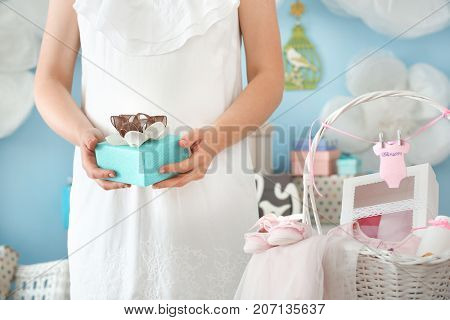 Pregnant woman holding gift at baby shower party indoors