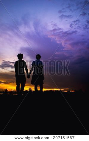 The girl and boy lover is stand and holding hand silhouette style with cloudy twilight style