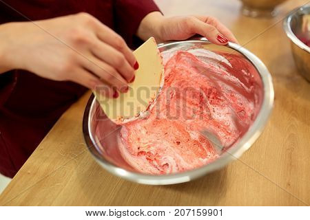 cooking, food and people concept - chef with spatula stirring macaron batter or cream in bowl at pastry shop