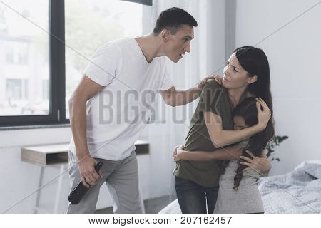 The Wife Is In The Bedroom And Protects, Embracing Her Little Daughter From The Evil Drunk Father