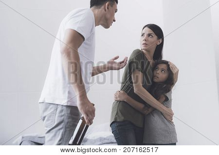 Evil Drunken Man With A Bottle In His Hands Screams At His Wife And Daughter Who Are Facing Him Embr