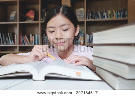 Girl Reading And Writing In Library Of School.