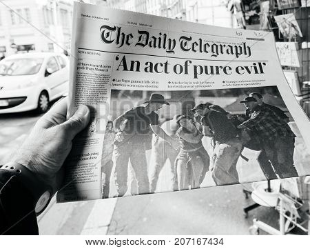 PARIS FRANCE - OCT 3 2017: Man buying The Daily Telegraph newspaper with socking title Pure Evil and photo at press kiosk about the 2017 Las Vegas Strip shooting in United States with about 60 fatalities and 527 injuries