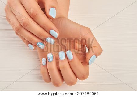 Female hands with winter nail design. Young woman hands with beautiful blue manicure. Gentle winter manicure close up.