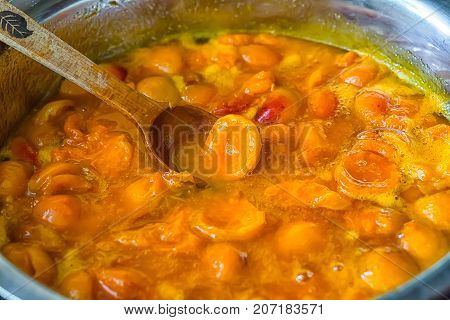 Apricot jam cooked in a bowl and jammed with a wooden spoon