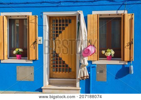 Blue house with flowers on sills in Burano Venice.