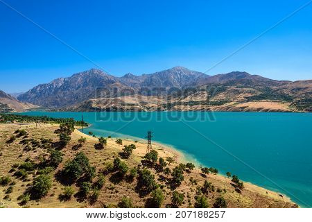 Panoramic view of Charvak Lake, artificial lake-reservoir created by erecting a high stone dam on the Chirchiq River, and range of mountains on the background located in Tashkent region of Uzbekistan