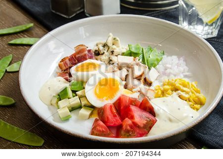Healthy Hearty Cobb Salad with Chicken Bacon Tomato Onions and Eggs. American food. Close up, home made