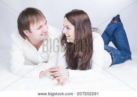 Family Lifestyle Ideas. Smiling and Laughing Caucasian Couple Having Time Together. Communicating on Floor And Looking Into Eyes of Each Other and Holding Hands In Touch. Horizontal Image Composition