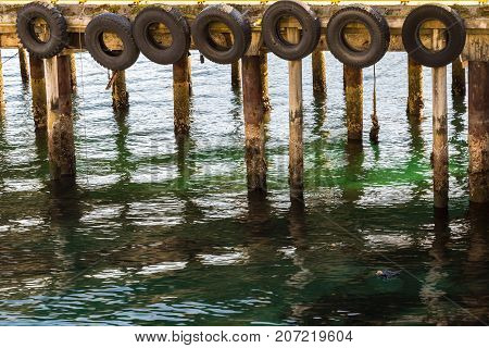 Pier lined with tires as fenders for the boats docking on them, close view, Harstad in Norway