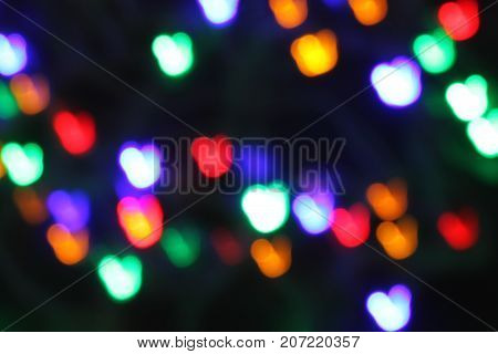 Bokeh of multicolored hearts on a black background. Celebration atmosphere.