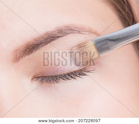 Young girl using brush and applying eyeshadow.