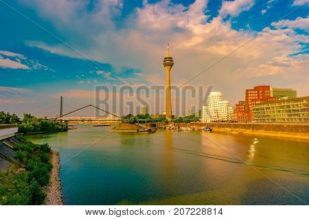 Looking at Media Harbor at Rhine-River in Dusseldorf in Germany. Media Harbor with Rhine-Tower and famous buildings in gentle sunset light with their reflection in the water. Beautiful and colorful cityscape of the german city