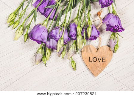 Delicate purple flowers and a wooden heart. Romantic concept