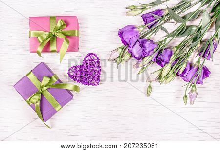 Gifts and flowers. Boxes with gifts and a bouquet of flowers eustoma on a white background. Wicker heart. Romantic concept.