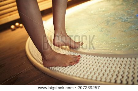 Woman with beautiful legs entering hot tub in spa resost