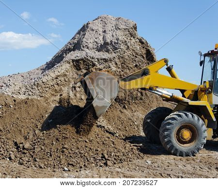 Wheel excavator digging gravel pile for loading in the truck