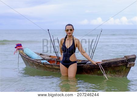 Woman sexy black bikini and small boat on beach at Ban Krut Beach Prachuap Khirikhan Province Thailand